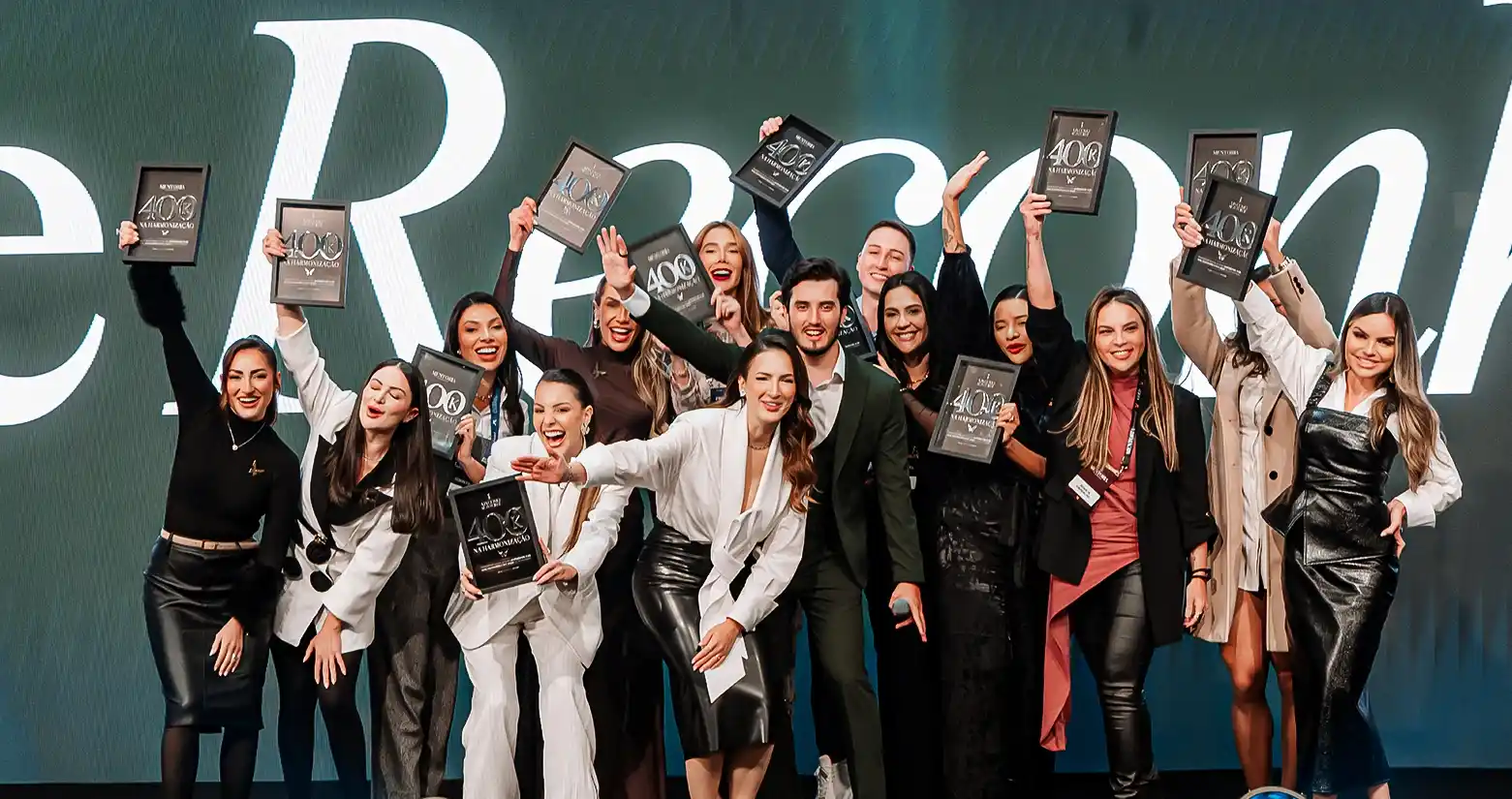 Alunas e alunos no palco do First Class com as placas de resultado